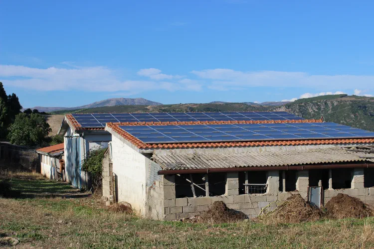 Pannelli fotovoltaici sul tetto di un fabbricato rurale, con le colline sullo sfondo